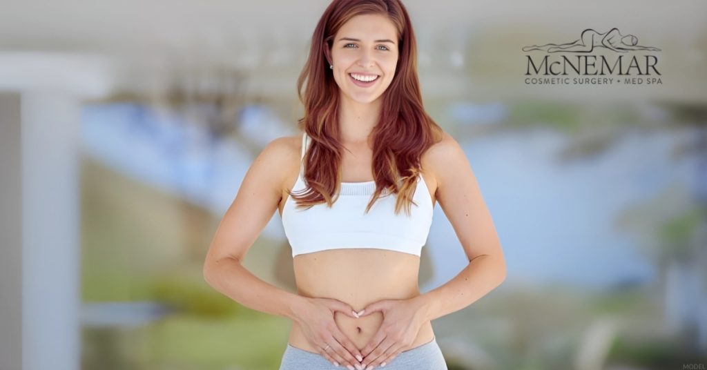 Woman with hands forming a heart shape over her abdomen (MODEL)