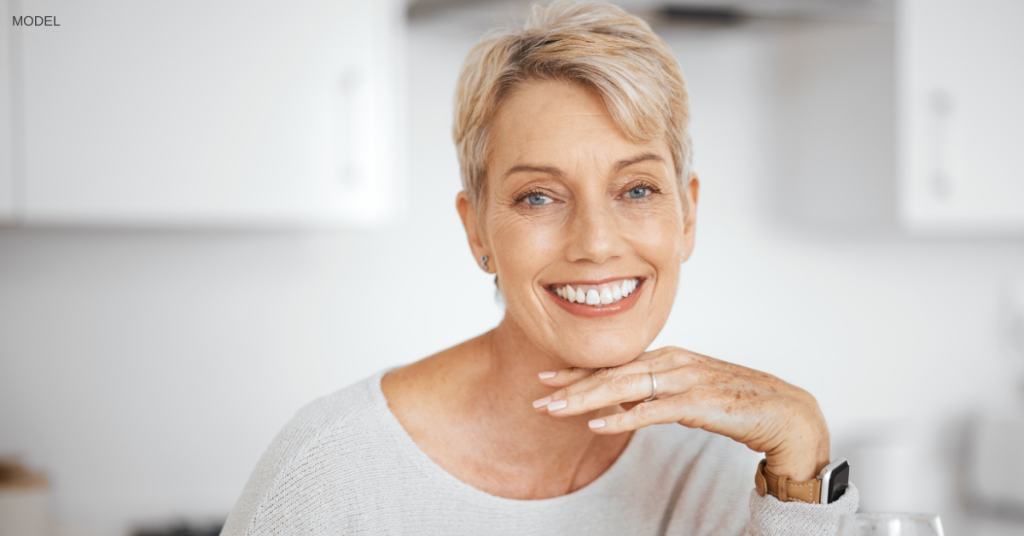 woman (model) smiling with hand under her chin in the kitchen