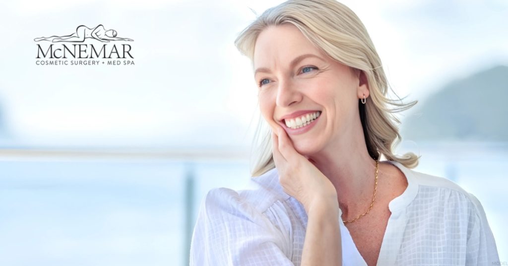 Woman smiling with their hand on her chin (model)