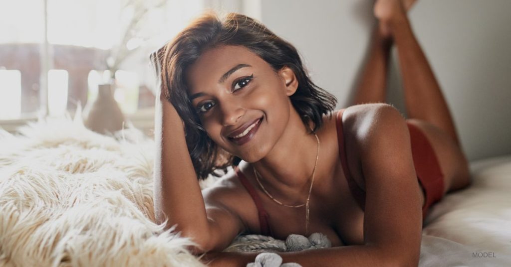Woman (model)_ lying on bed and smiling.